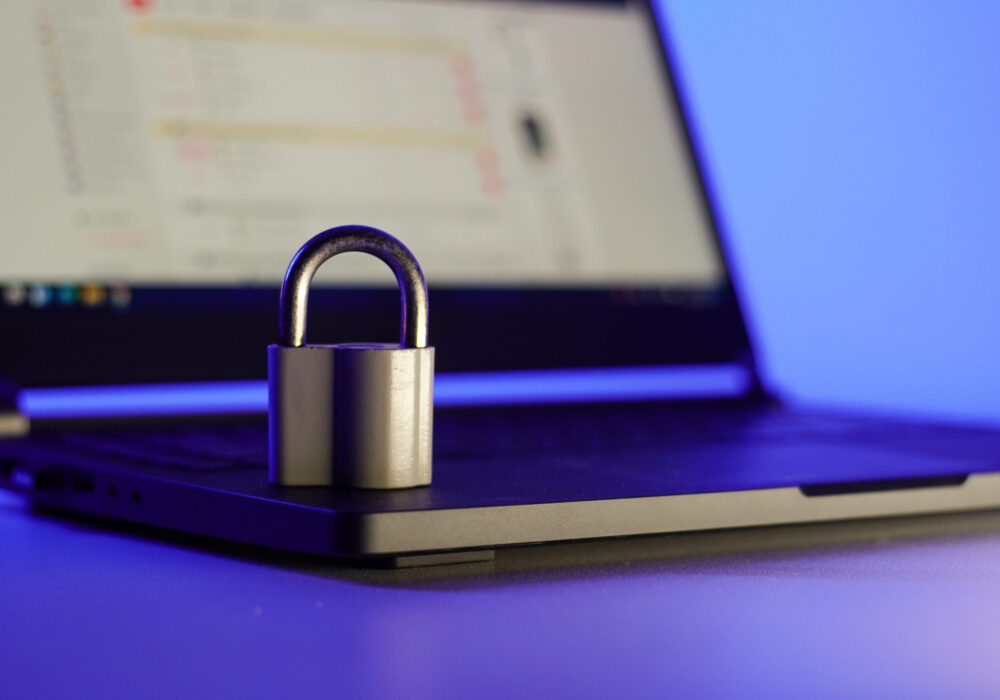 Locked metal padlock on a laptop keyboard over blue background. Cyber security, antivirus software concept.