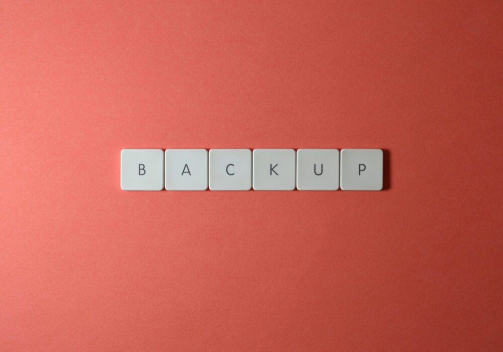 Free Close-up of keyboard keys spelling 'BACKUP' placed on a coral-colored surface. Stock Photo
